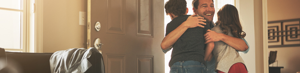 Kids hugging their dad in doorway